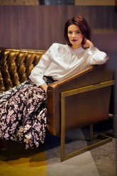 a lady in a white shirt with ruffle and a floral printed skirt